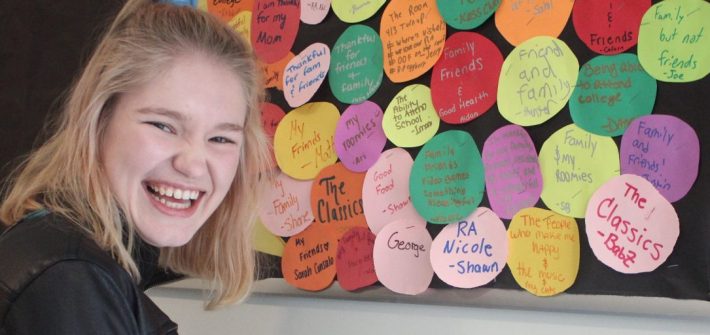 Nicole Grant laughs as she stands in front of a colorful bulletin board she made as a resident assistant.