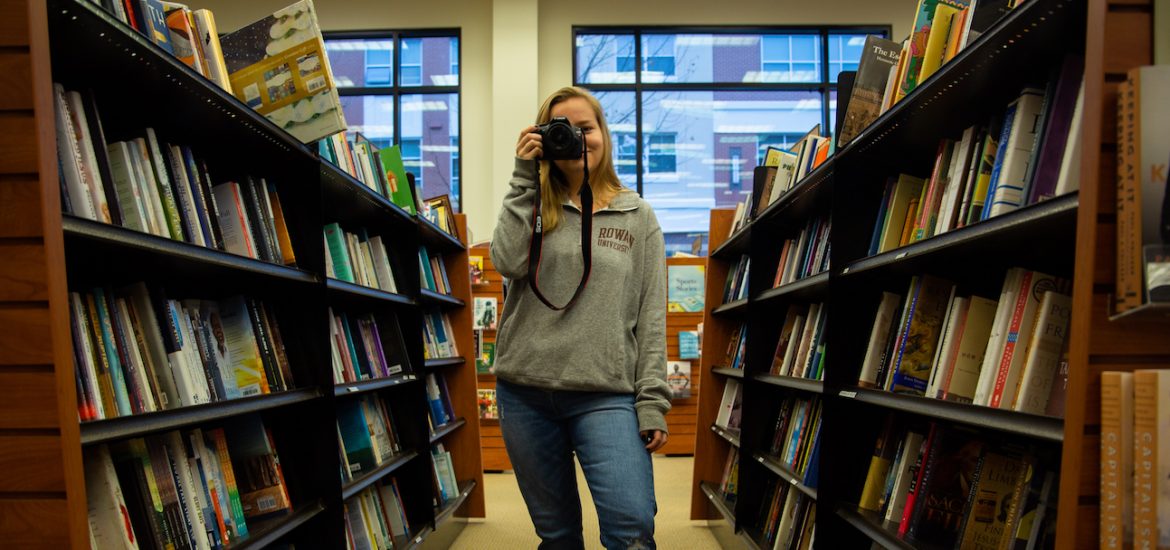 student inside Barnes and Nobles on campus in book aisle taking a photo
