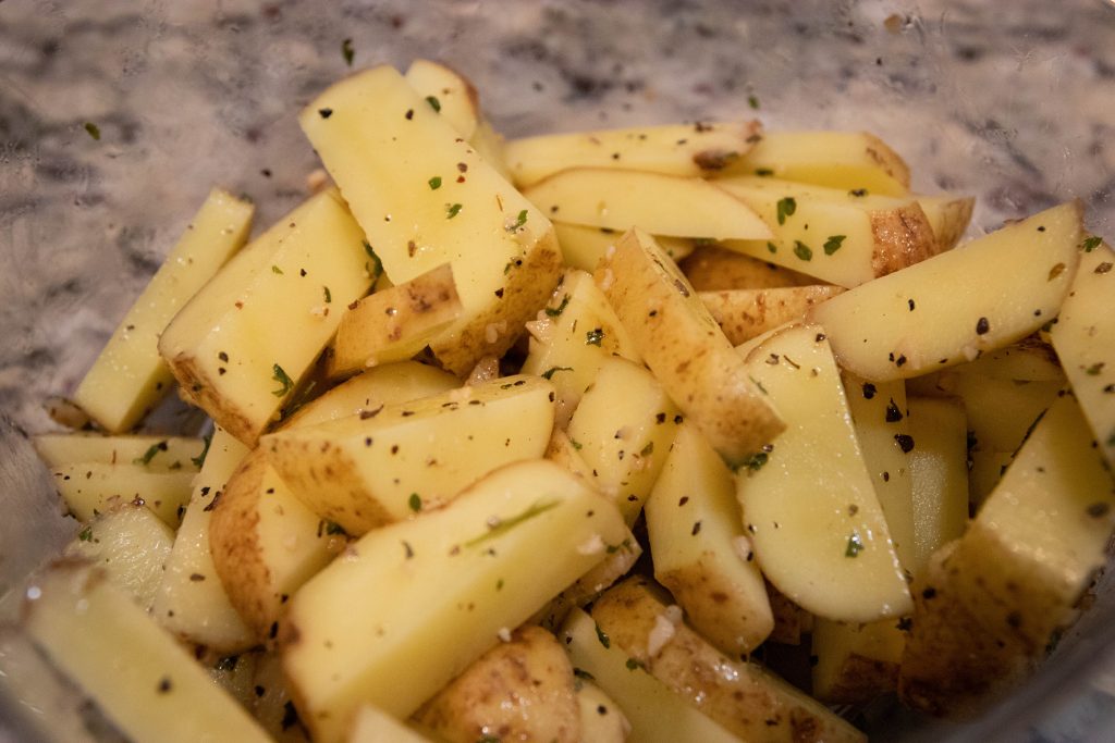 Seasoned potato slices in a bowl.