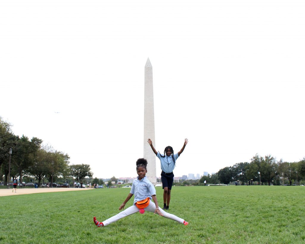 photo Kailey took of two children playing on the green grass outside the Washington Monument 