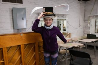 Student Isabel wearing a prop hat inside the rehearsal room