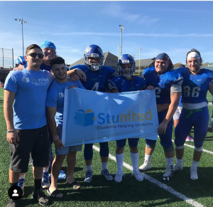 Stunited flag being held by college football players outside