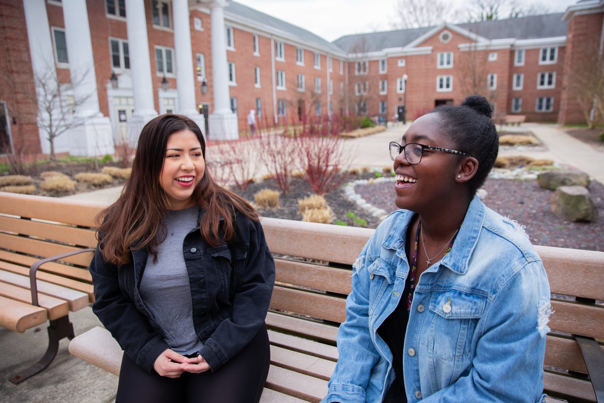 Jenn Cruz and Edris Forde laughing on a bench outside Chestnut Hall.