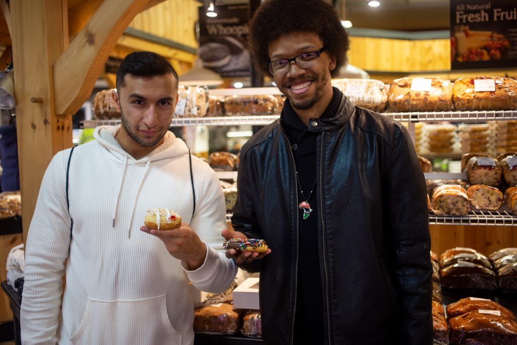 two friends holding donuts inside the Farmer's Market