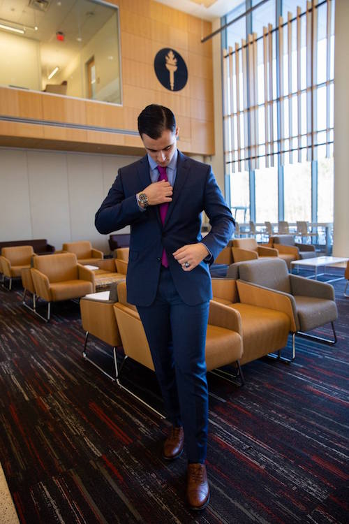 Junior marketing major Dan looks down to adjust his tie in Business Hall