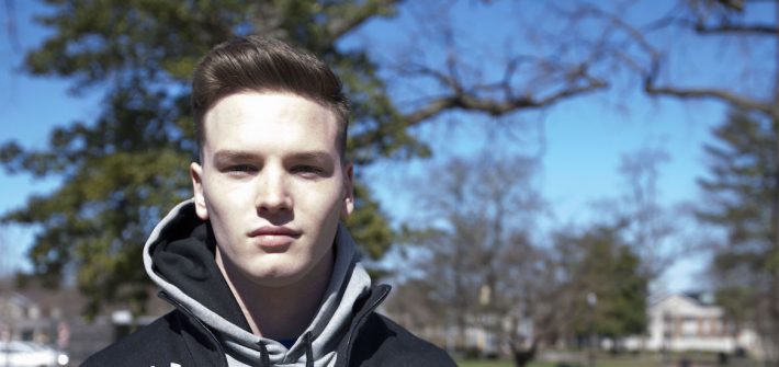 Francis Terry stands in front of a tree for a portrait, wearing a black Rowan zip up