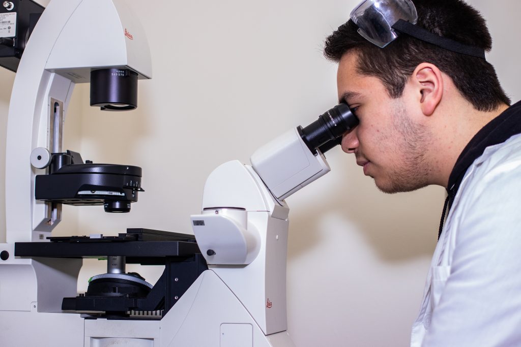 young male student looking into a microscope