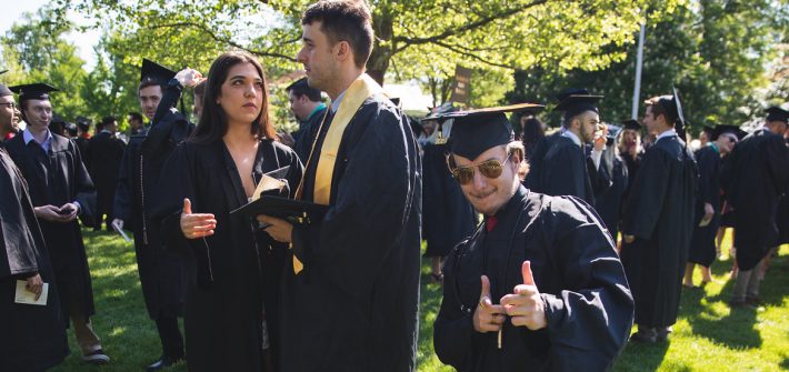 Radio/Tv/Film graduate poses in his black cap and gown.
