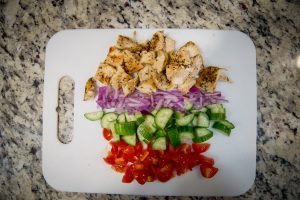 A combination of cut chicken, onion, cucumber, and tomatoes