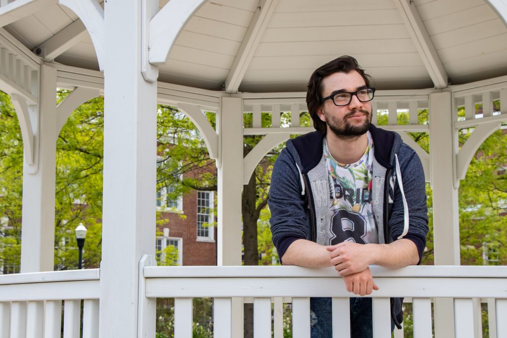 Young male student inside a white gazebo leaning against the railing