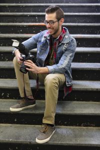 Alex using a dslr and flash, sitting on a staircase.