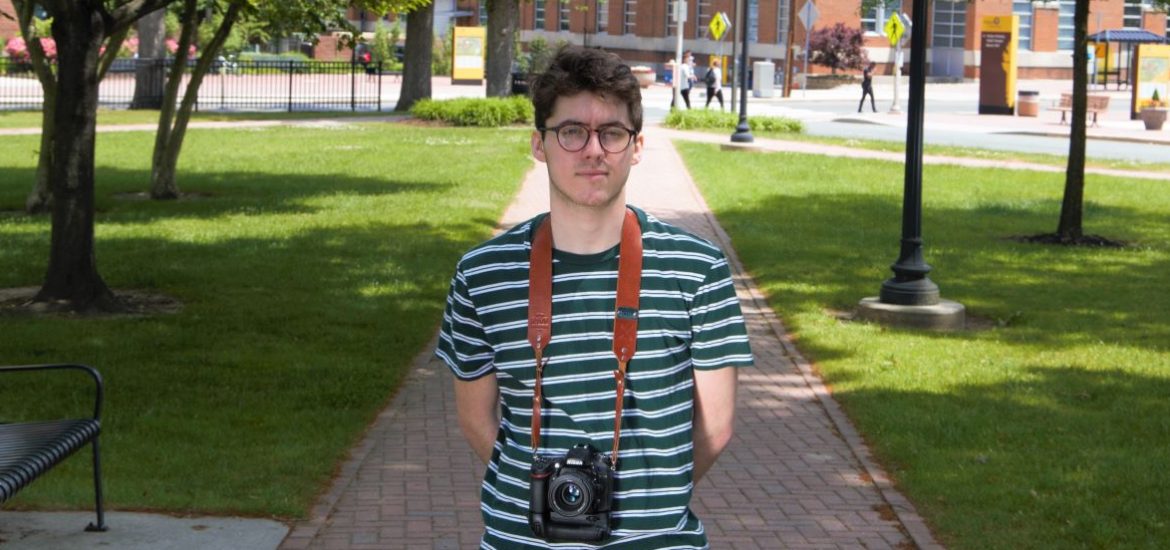 Chad, standing in the gradd of bunce hall with a camera