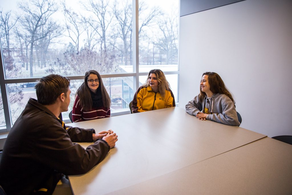 Rowan students talking in a meeting room.
