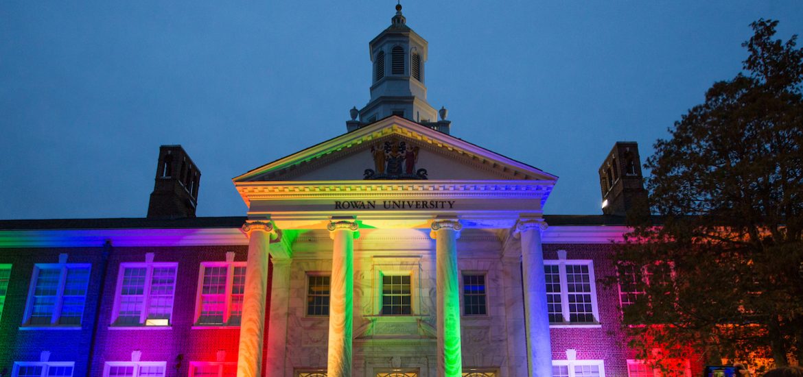 The front of Bunce Hall being lit up at night with rainbow colored lights