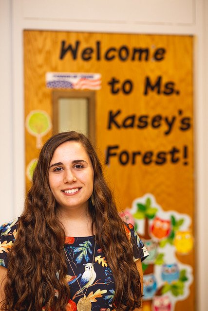 Kasey DiSessa of Rowan University stands in front of her decorated classroom door that says Welcome to Ms. Kasey's Forest!