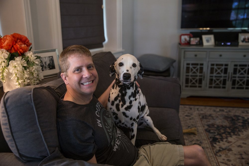 Steve and Lola the Dalmatian sitting on a grey couch.