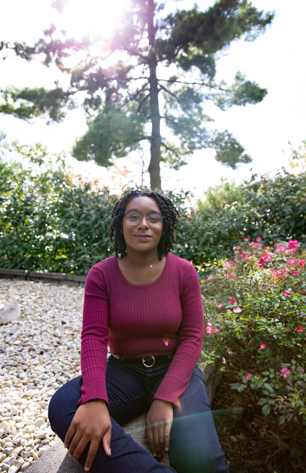 Higher Education Administration track graduate student Jessica Hassell sits near a bush on Rowan University's campus.