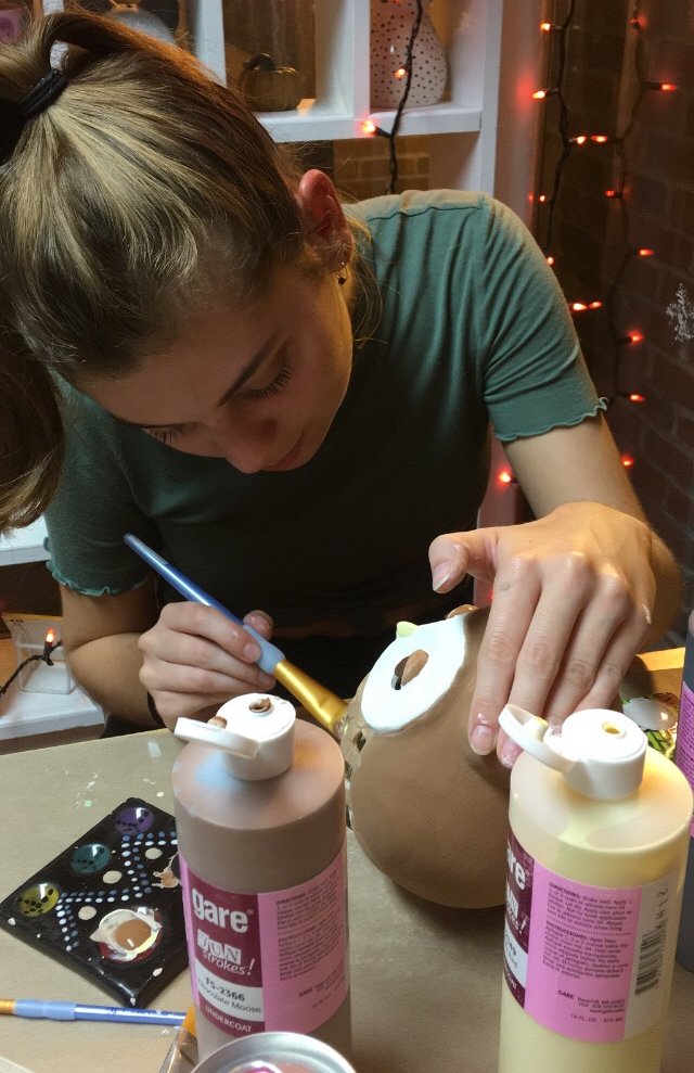Rowan student Alyssa B. painting an owl at Fahrenheit Ceramic Studios.
