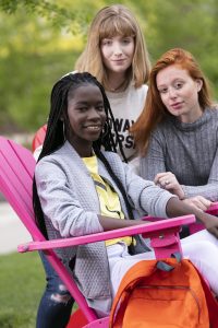 Mary and two students sit on a pink chair