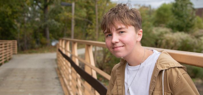 Rowan psychology major Caleb Jones stands in front of a footbridge on campus