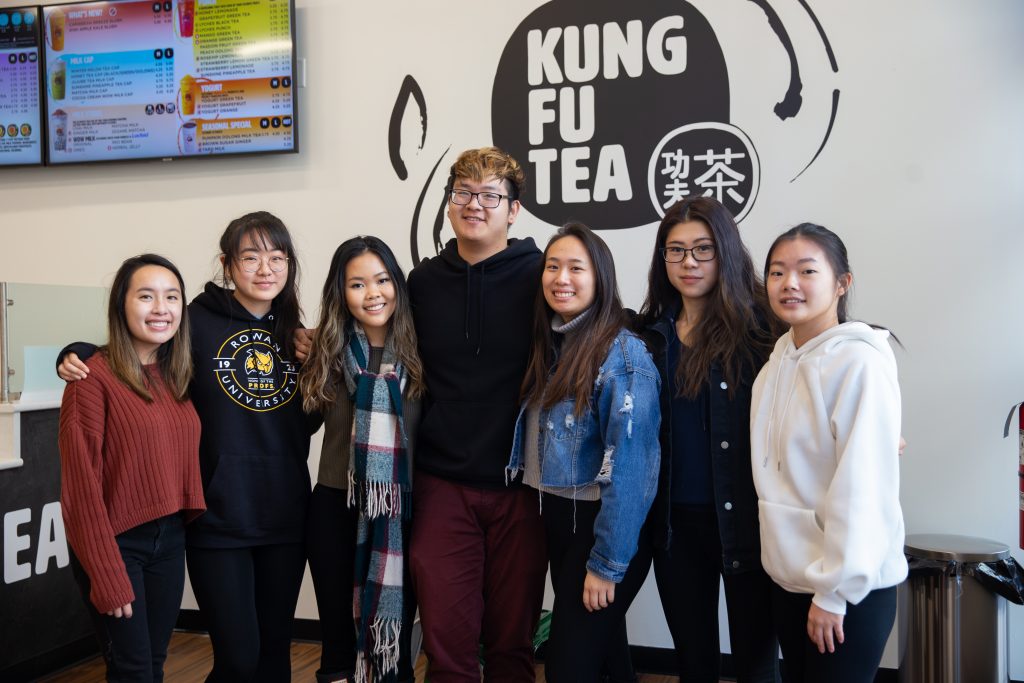 Seven friends and members of the VSA eboard stand together at Kung Fu Tea on Rowan Boulevard