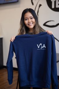 Biological Sciences major Brianna Nghiem holds up a T-shirt with the Vietnamese Student Association logo on it.