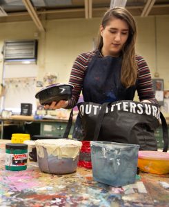 Leann arranges tubs of colorful paint on a table in the studio at Westby Hall