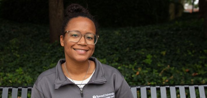 Autumn Vilches-Cruz, junior Psychology major, sitting on a bench outside on Rowan's campus
