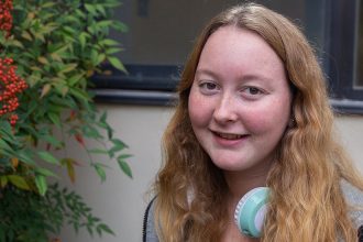 Freshman Public Relations major Rachel Rumsby sits on a bench outside on Rowan's campus.