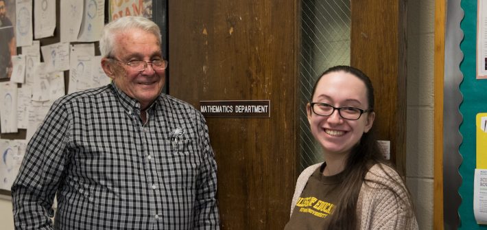 Adriana and Professor Smith smile in front of the Mathematics suite.