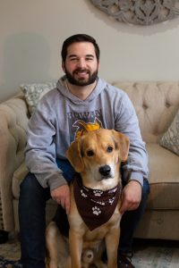 Gene sitting on the living room couch with his dog, Carsen sitting in-between his legs.