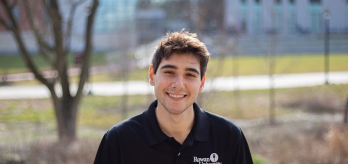 a male student sitting outside on a sunny day.
