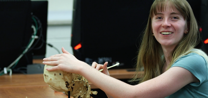 Emily carving a clay skull in a classroom.
