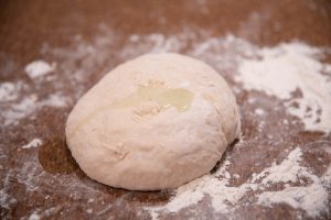 Pizza dough kneaded into a ball with a dab of olive oil on top.