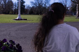 Girl stares into the distance as we see the back of her head and ponytail.