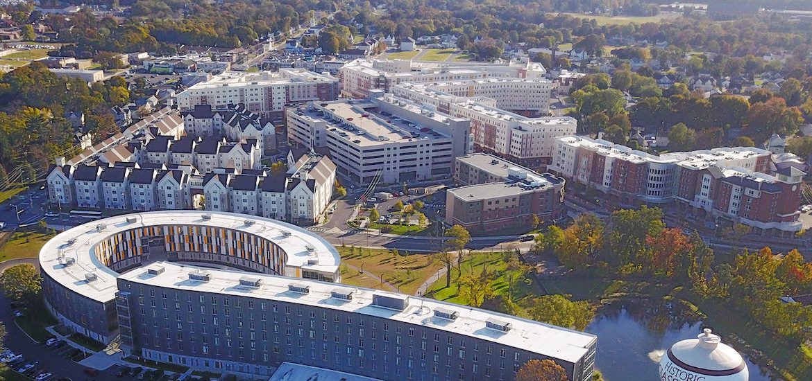 Drone view of Holly Pointe curved building with trees in the horizon.