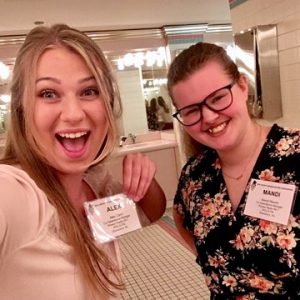 Amanda and her friend, Alex, hold up their nametags at an event.