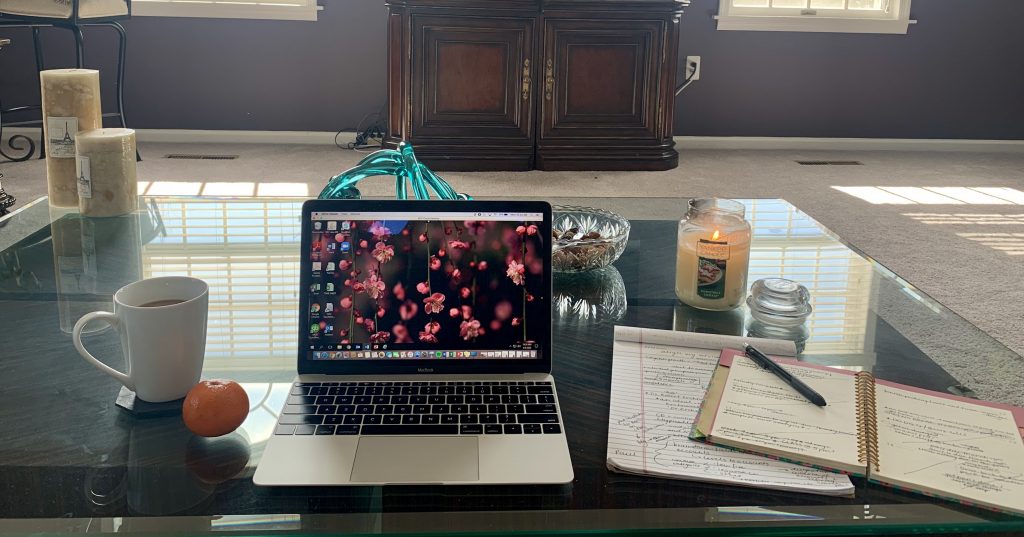 Alyssa's tidy and bright work space which includes a laptop, notebooks and scented candles.
