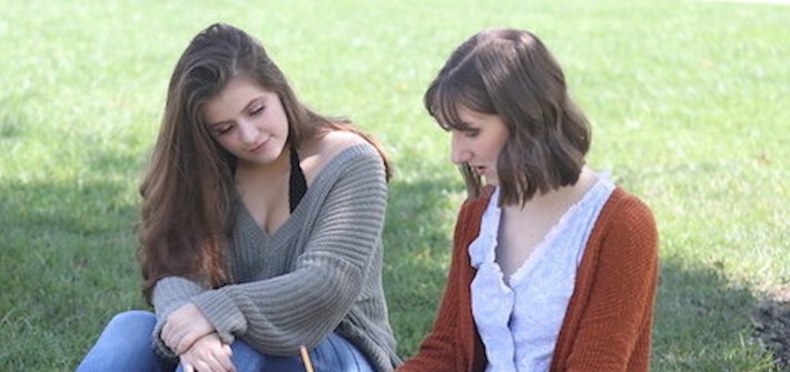 Hannah and friend sit outside on-campus.