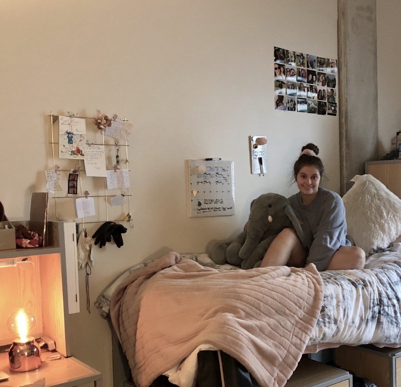 Hannah posing on her bed in her Holly Pointe Commons dorm.