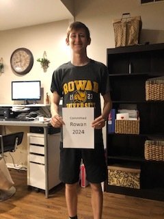 Shane stands holding a homemade sign that says Rowan2024.