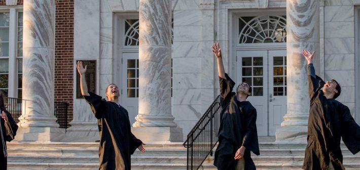 four grads toss their hat.