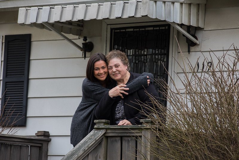 Maria wraps her arms around Nonna outside their home.