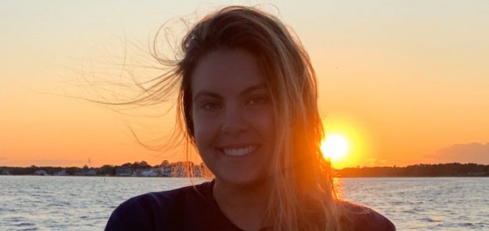Taylor Melillo in front of a sunset on the water.