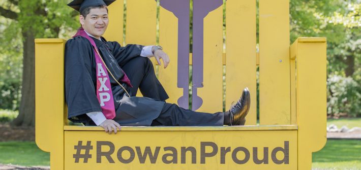 Health promotion and wellness management major Eric Chen posing on the Rowan Proud yellow chair.
