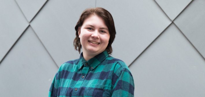 Marissa poses for a portrait while wearing a green plaid shirt.