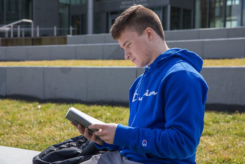 Tyler sitting reading a book in front of Business Hall