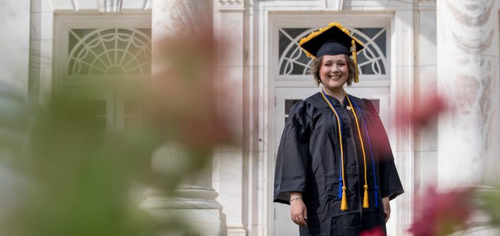 Chelsey Fitton stands in her cap and gown outside of Bunce Hall