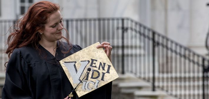 Sarah Transue holds her decorated cap in front of Bunce Hall