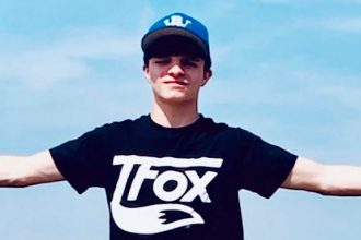 Photo of Anthony with his hands stretched out wearing a black t-shirt